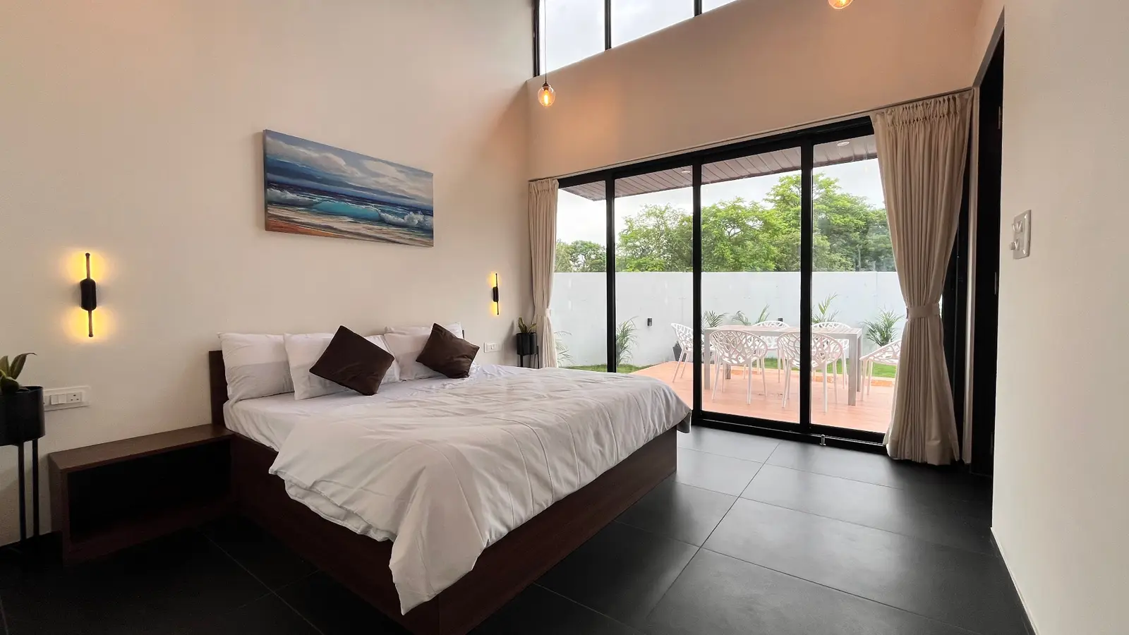 Reference photo 1a: bed with white linen, ocean painting, glass doors to patio